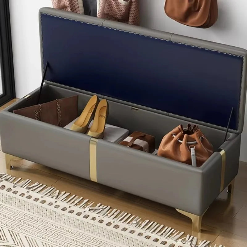 Angled view of storage ottoman with lid up, storing shoes and bags