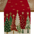 Red Christmas table runner with multicolor evergreen tree and gold star pattern draped on a wooden table