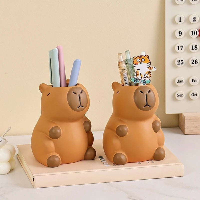 Two capybara-shaped pen holders organizing stationery on a desktop
