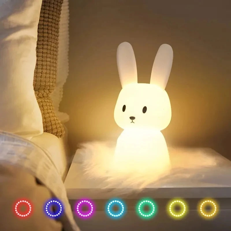 Bunny-shaped silicone night light glowing softly on a bedside table, with color mode indicators below