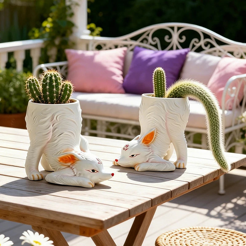 Pair of fox-shaped planters with cacti on a wooden outdoor table with patio seating