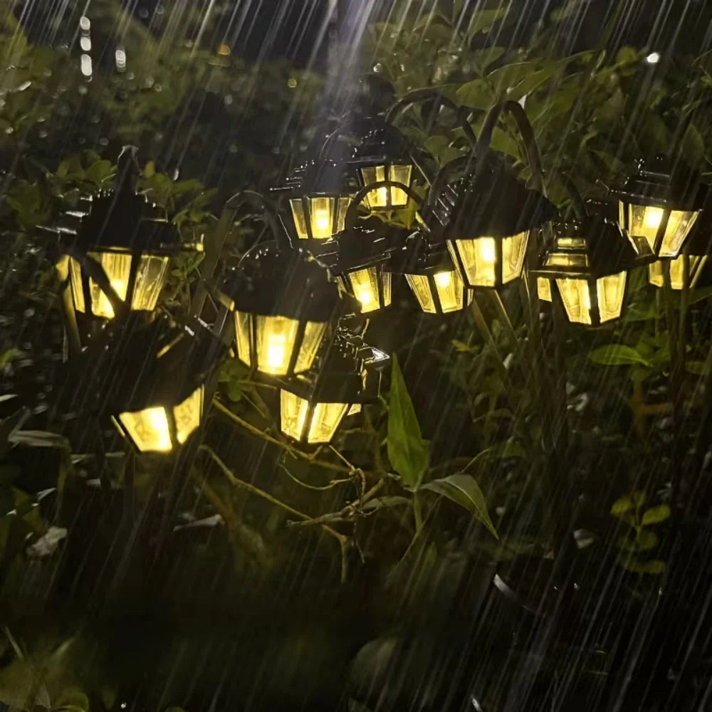 Solar lantern stake light glowing in the rain among garden plants, showing water resistance