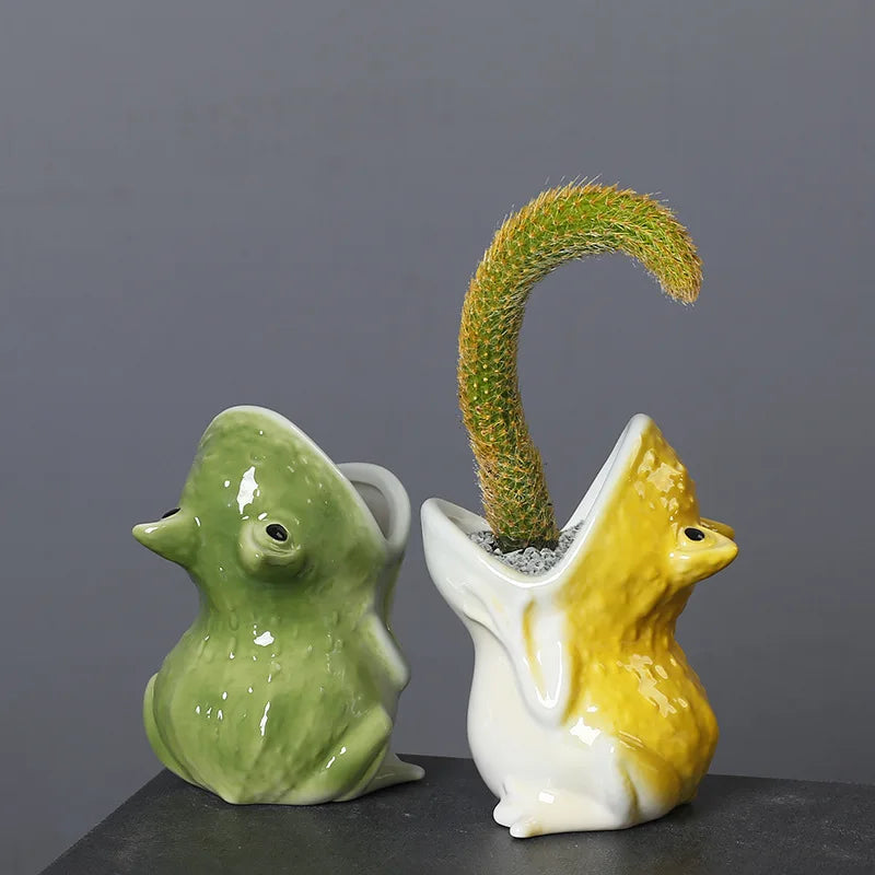 Green and yellow ceramic frog planters, one with a cactus plant