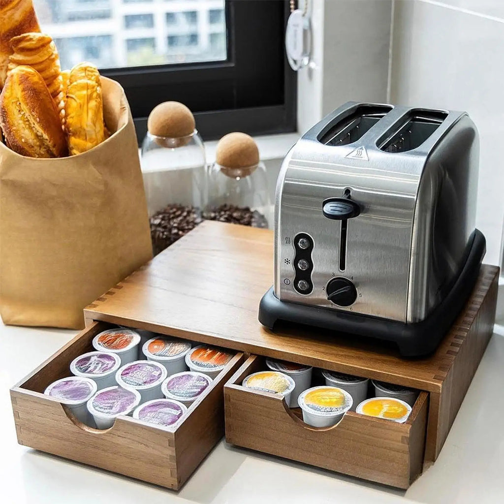 Toaster on top of the wooden pod organizer with both drawers pulled out holding coffee pods