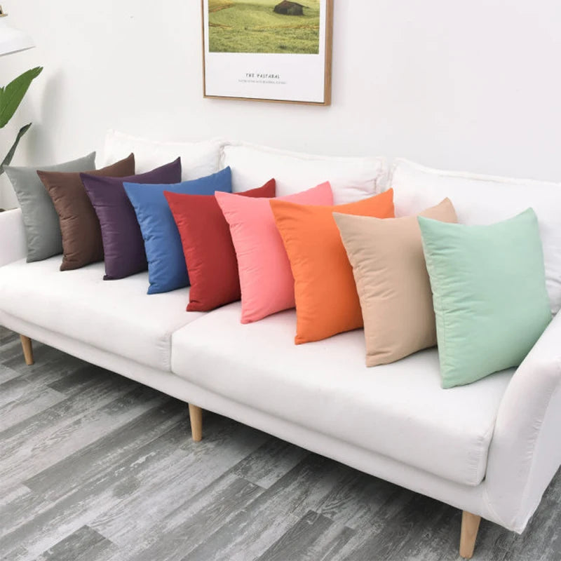 Row of solid color outdoor cushion covers on a white indoor sofa
