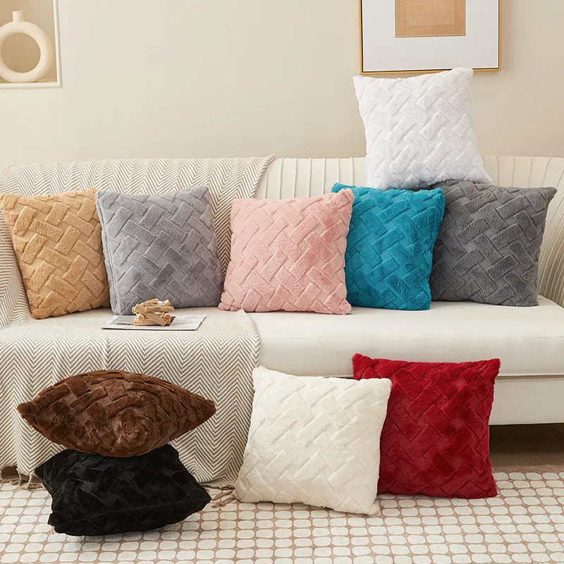 Assorted plush throw pillow covers in cream, gray, pink, blue, brown, black, camel, red, and white on and around a sofa