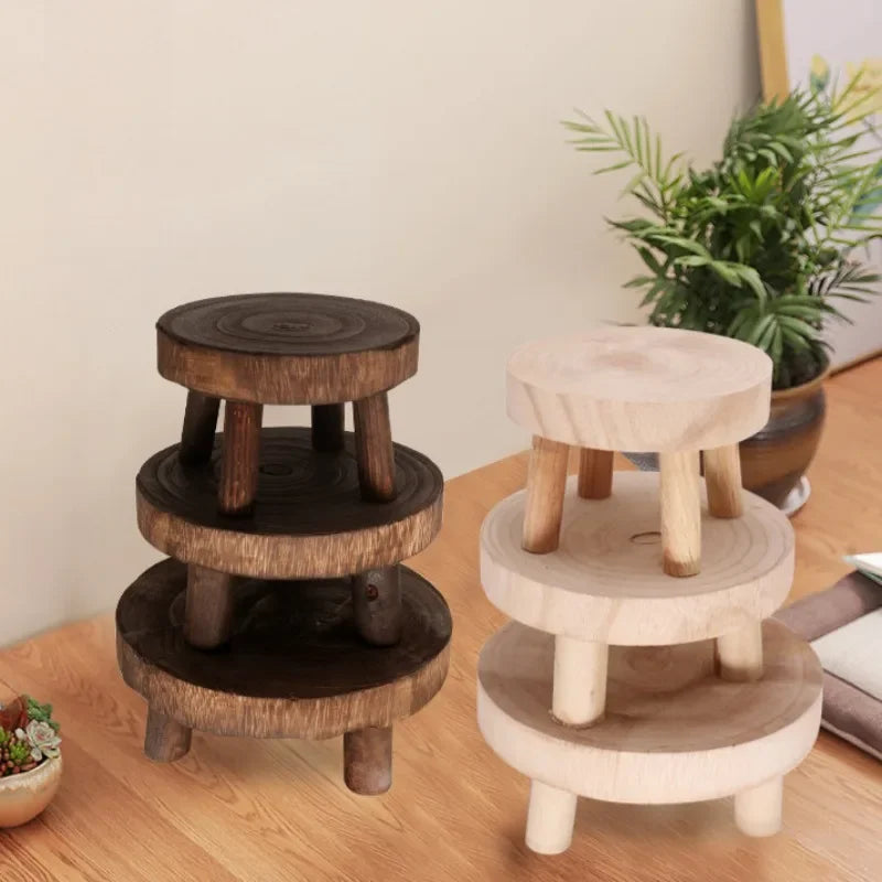 Two sets of small wooden plant stands, one dark and one light, stacked on a desk with plants.