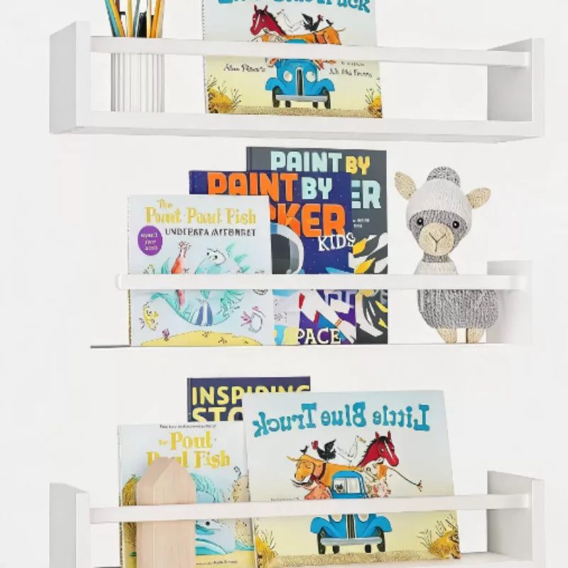 Set of white floating wall shelves used as children's bookshelves with picture books and soft toys.