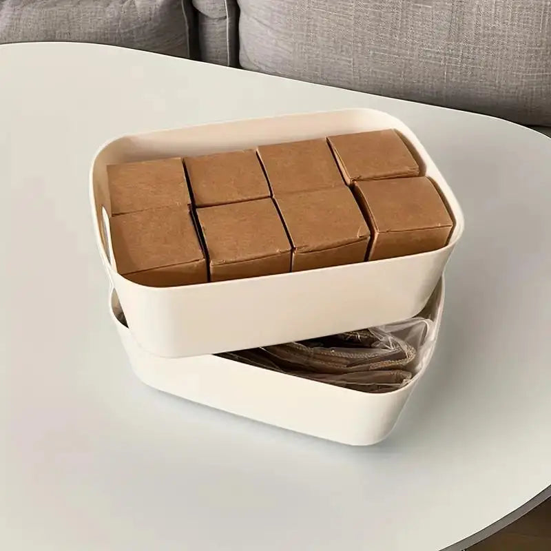 Two white plastic bins stacked, containing small boxes and items on a table