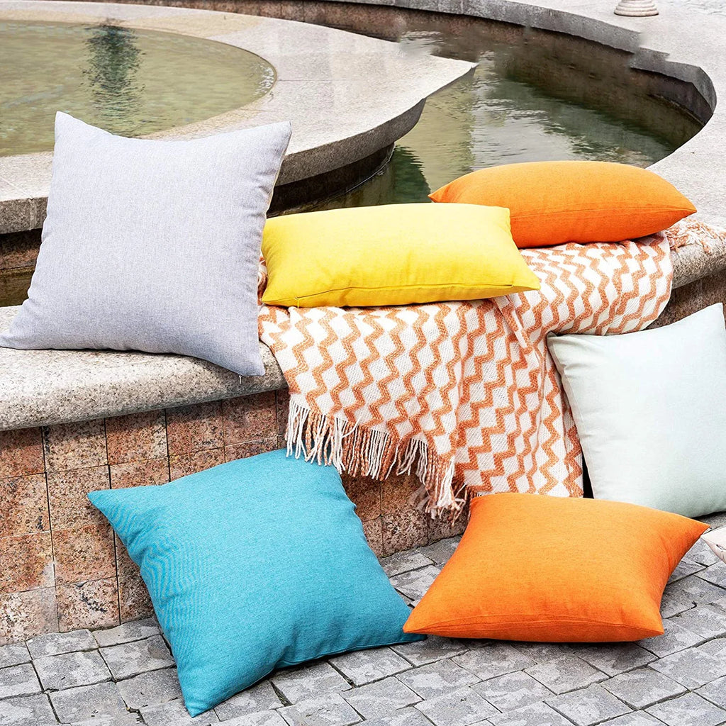 Assorted solid color outdoor waterproof cushion covers on patio bench and stones