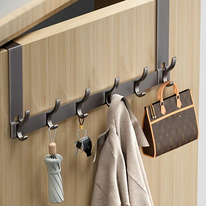 gray metal over-the-door hook rack with keys, umbrella, coat, and bag on interior door