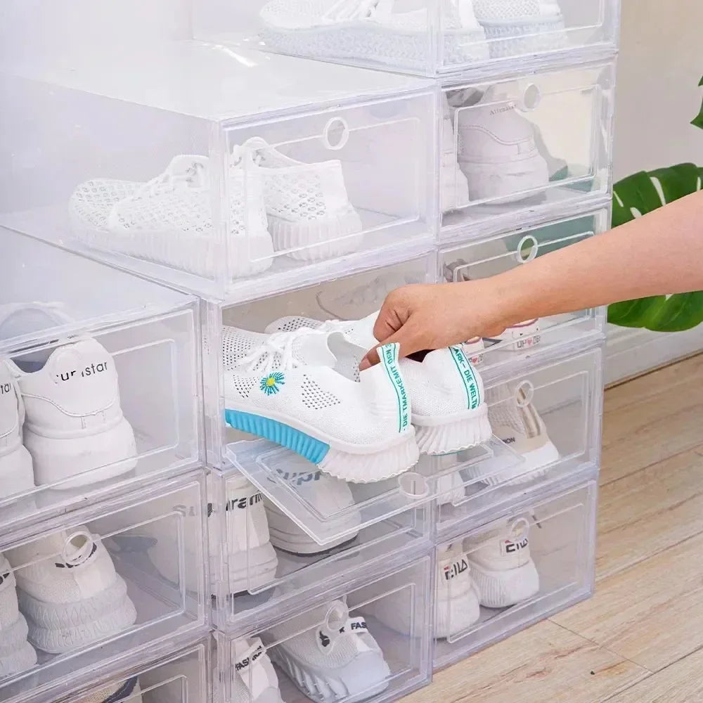 Hand pulling out a pair of sneakers from a clear plastic shoe box in a stack of multiple transparent shoe containers