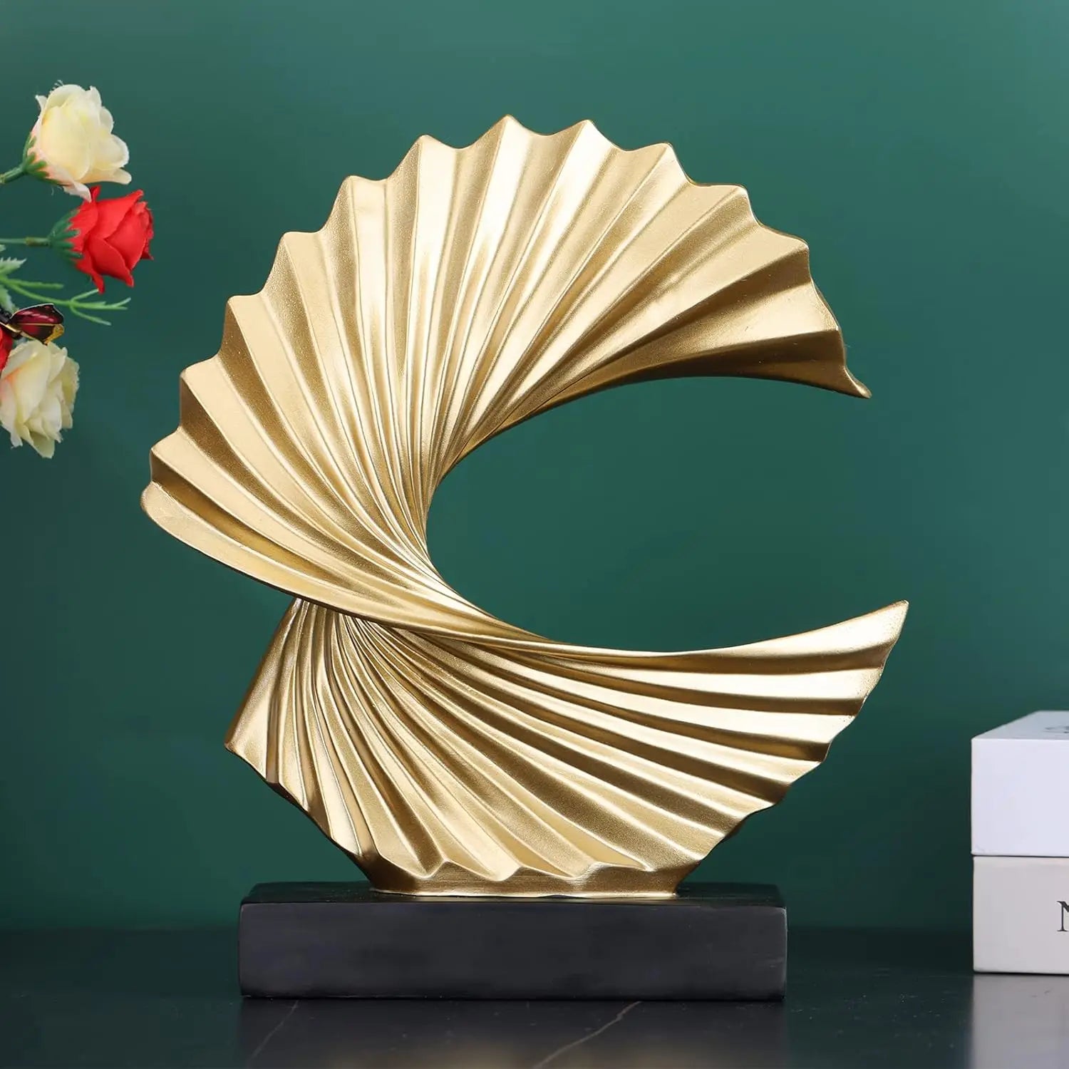 modern gold resin sculpture in front of green wall and vase, tabletop decor