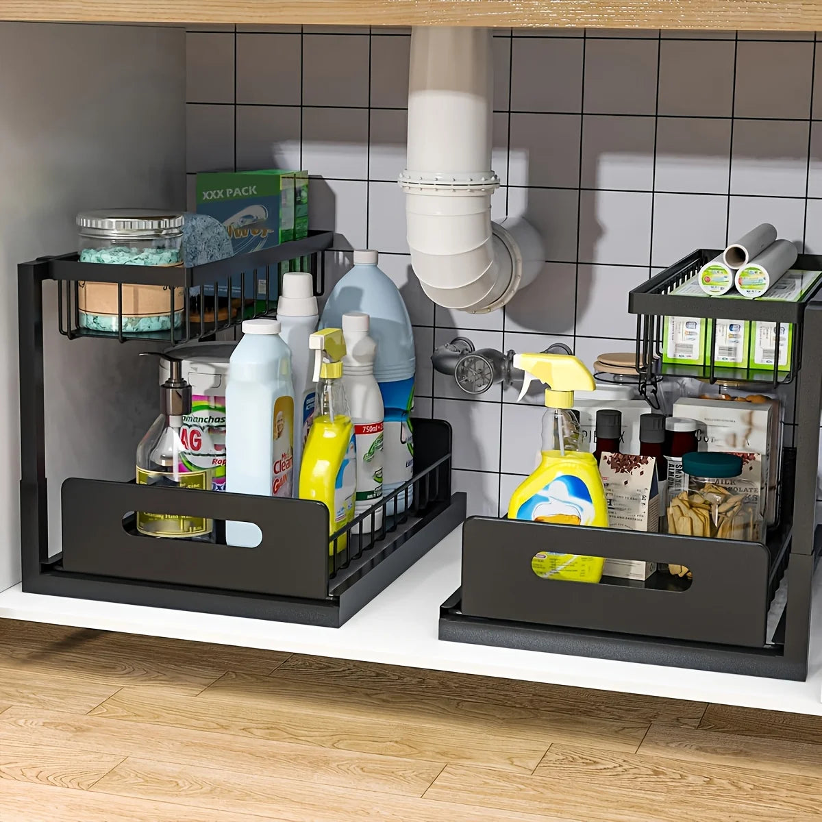 Two black steel under sink organizers in a cabinet, each storing bottles and spray cleaners