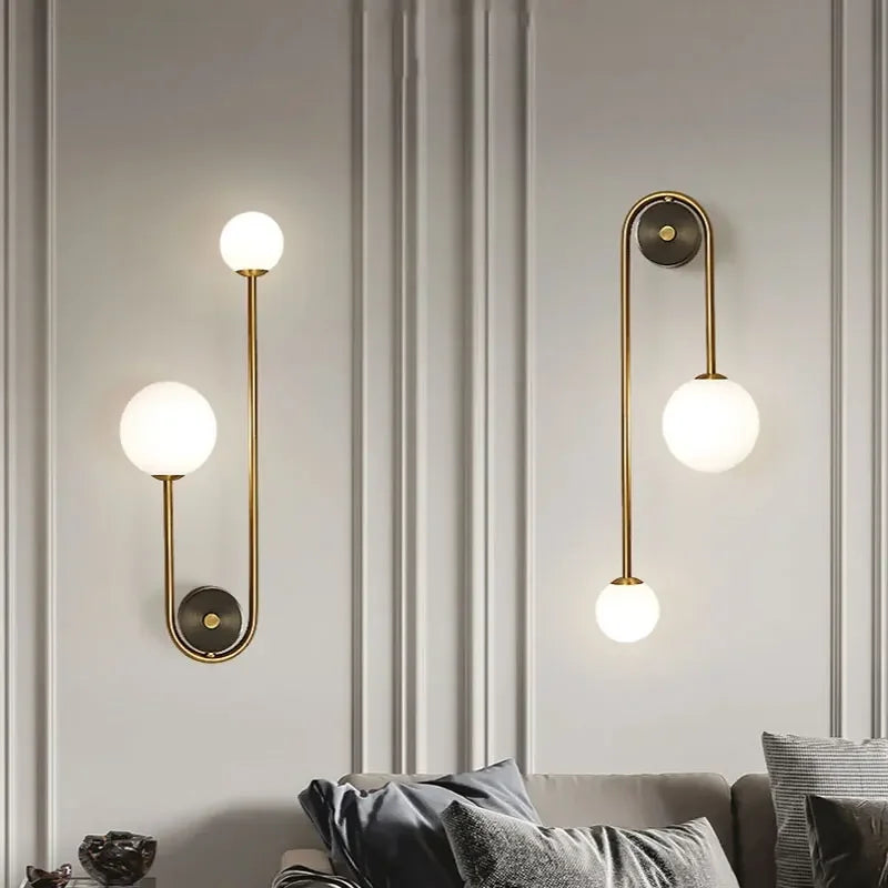 Pair of modern gold wall sconces with frosted glass globes above a living room sofa