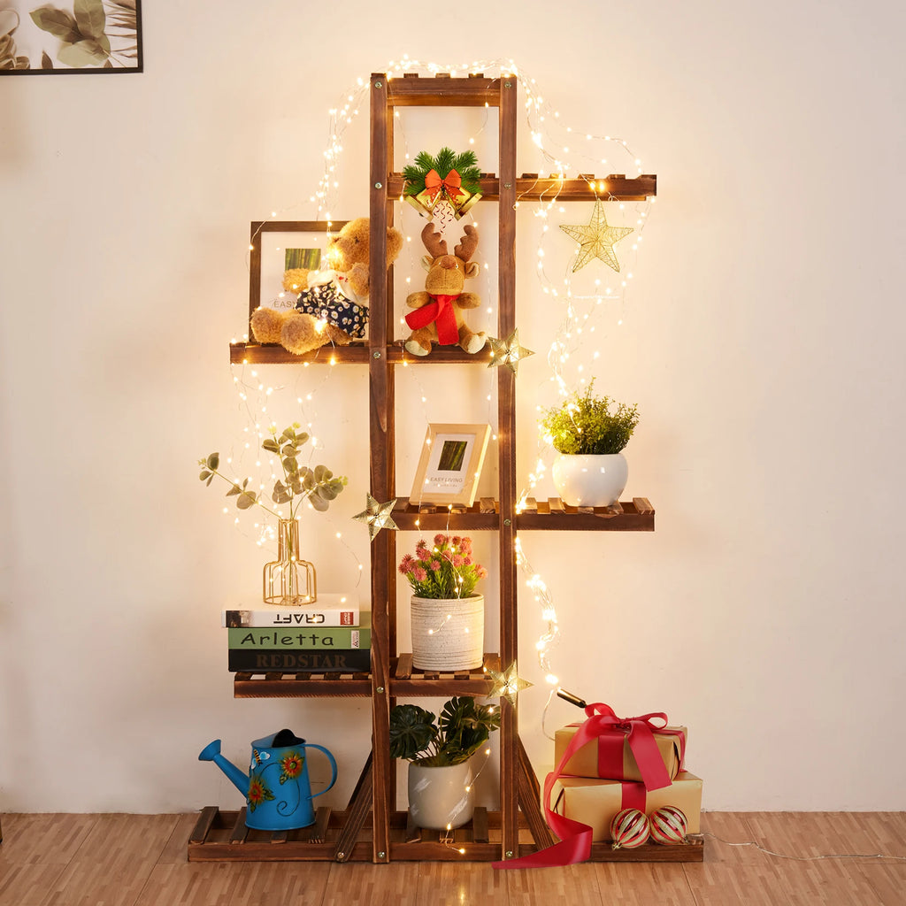 Wooden plant stand decorated with string lights, gifts, and small decorative items indoors