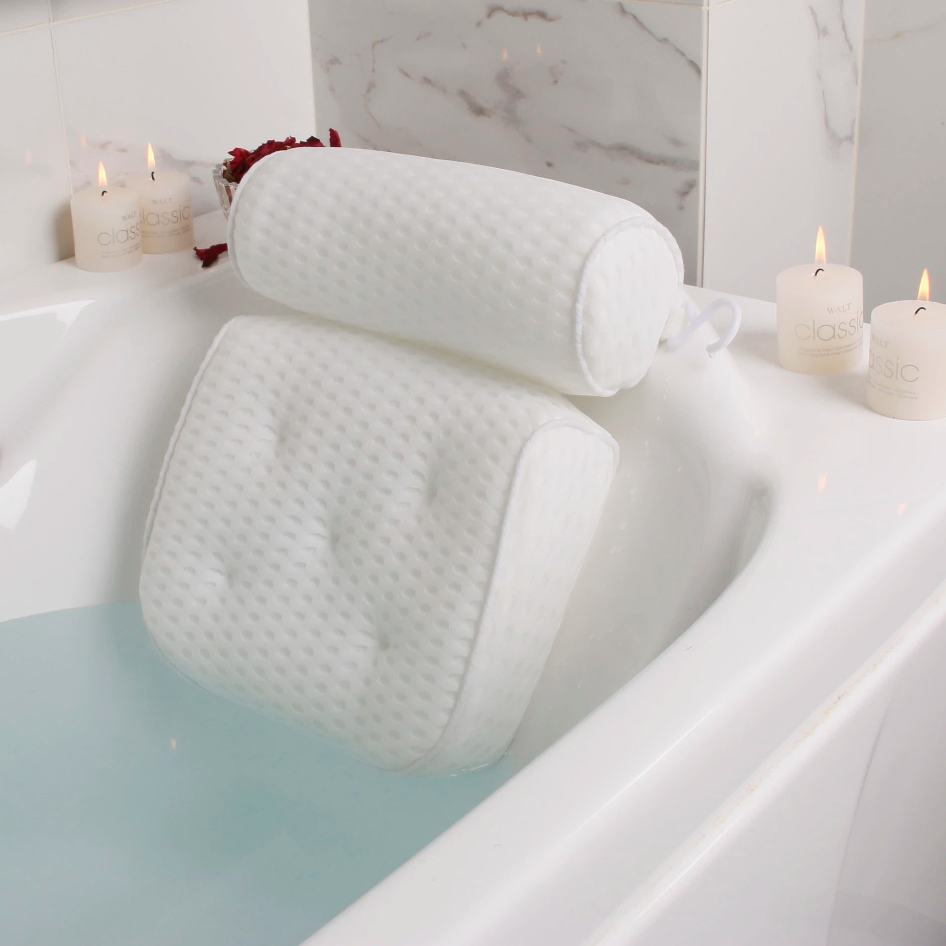 white air mesh bath pillow with neck and back support in a filled tub, surrounded by candles in a home bathroom