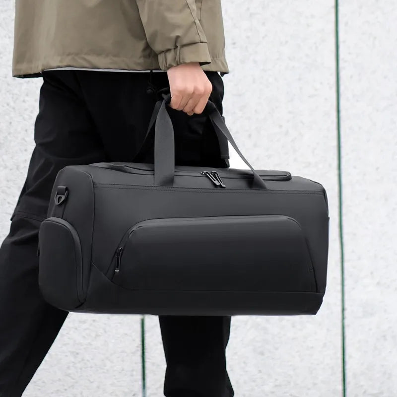 Person holding black duffel bag by the handles outdoors