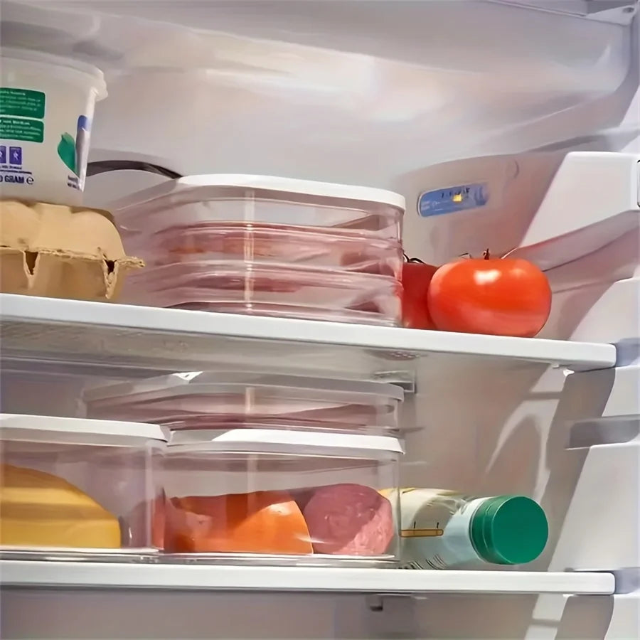 Two stackable clear meat containers in a refrigerator next to tomatoes and cheese
