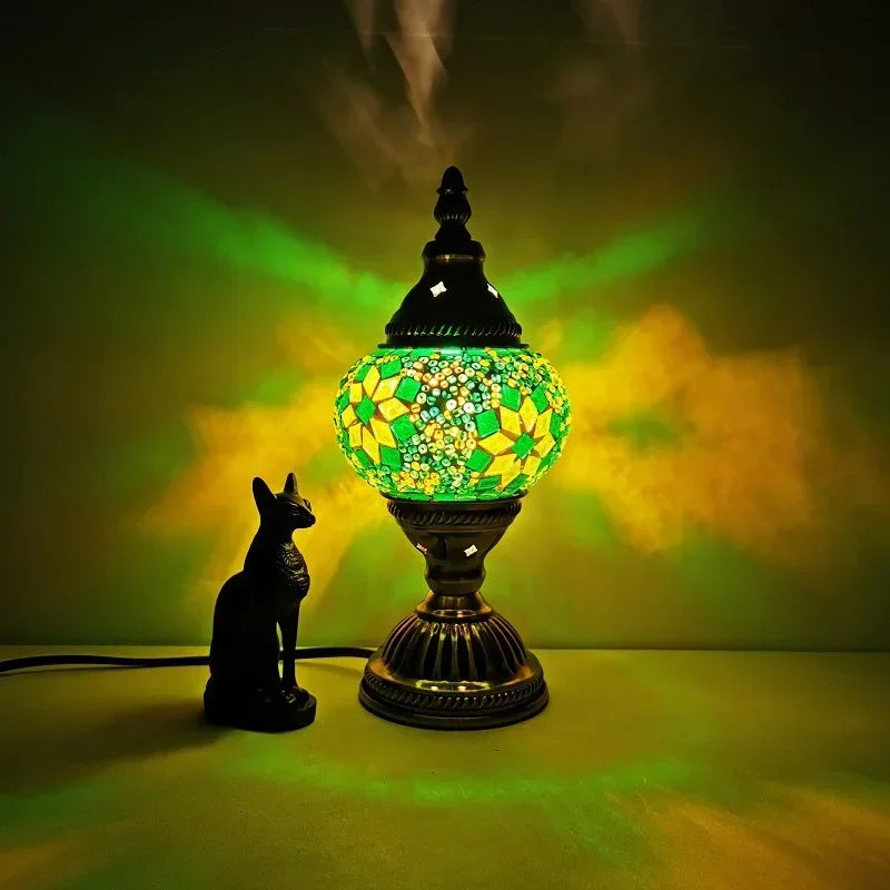 Stained glass mosaic table lamp with yellow and green mosaic pattern glowing on surface