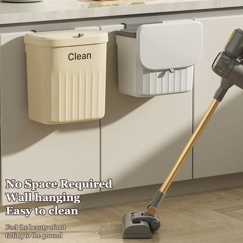 Beige and white hanging trash cans mounted on kitchen cabinet doors with a vacuum cleaning nearby, showing wall hanging use