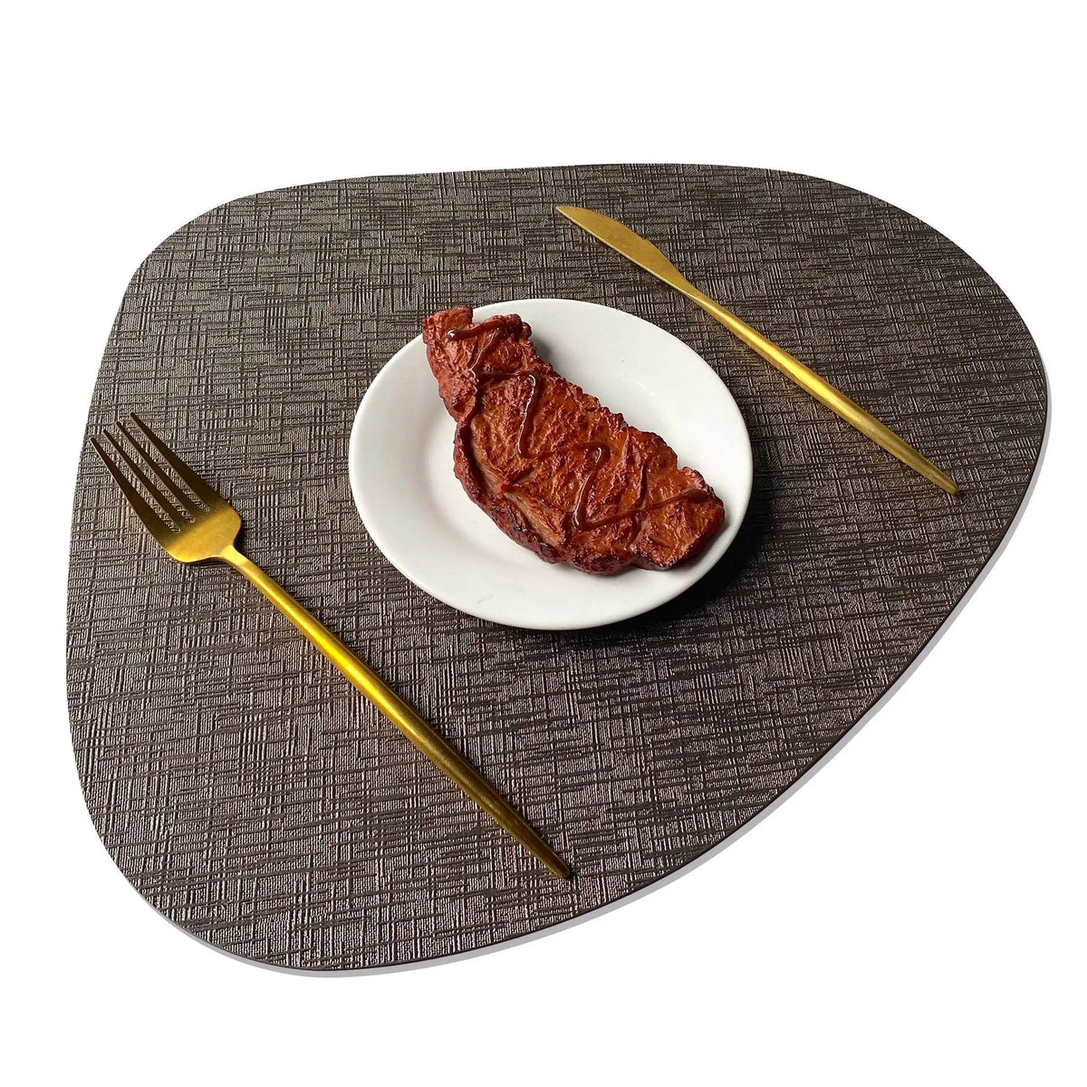 Single teardrop-shaped metallic placemat with gold utensils and white plate