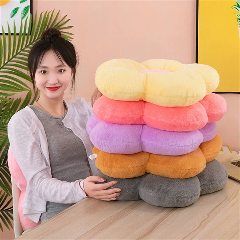 Stack of colorful plush daisy cushions in various colors on a table with person beside them