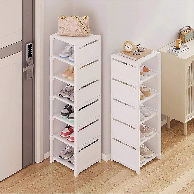 Two white slim vertical shoe racks side by side near an entryway, used for shoe storage.