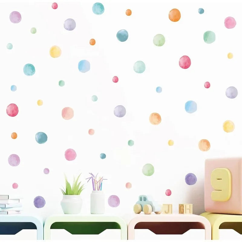 Boho rainbow watercolor polka dot wall decals in a nursery above pastel furniture
