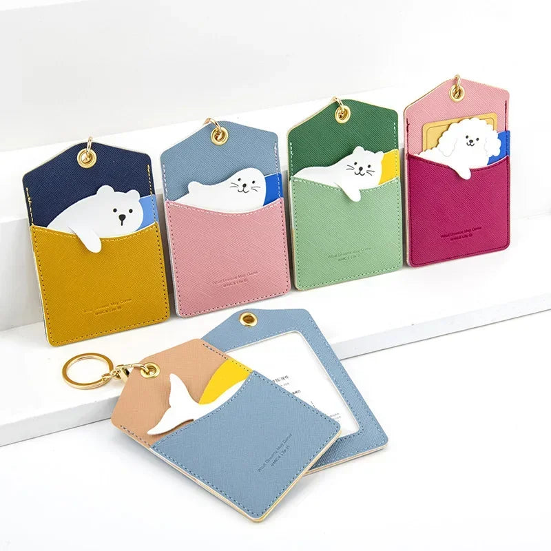 Five animal-themed card holder keychains arranged in a row, featuring seal, cat, poodle, and whale tail designs