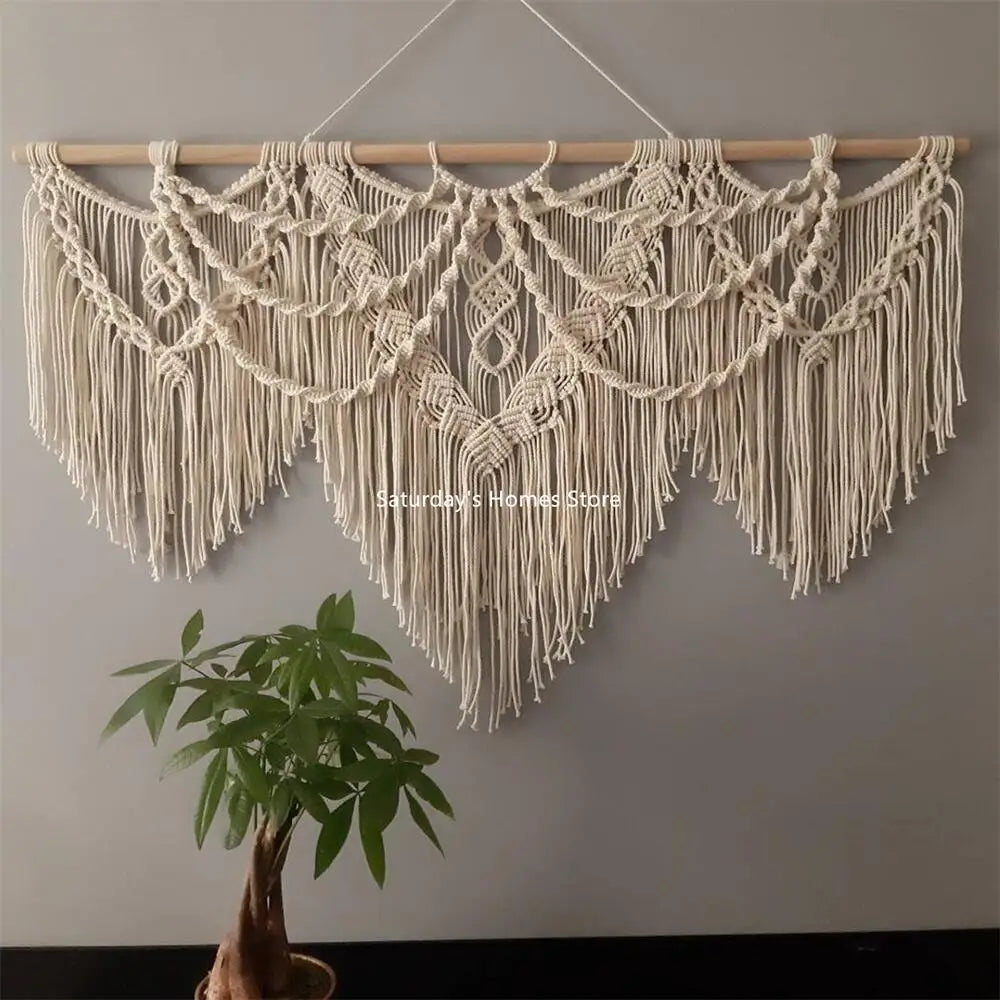 wide cotton fiber macrame wall art above green plant on neutral wall