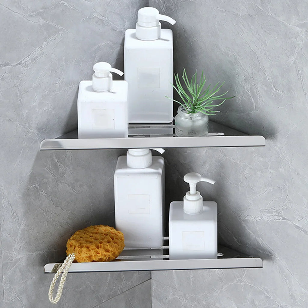 two silver stainless steel corner shower shelves holding white bottles and a sponge in a gray bathroom