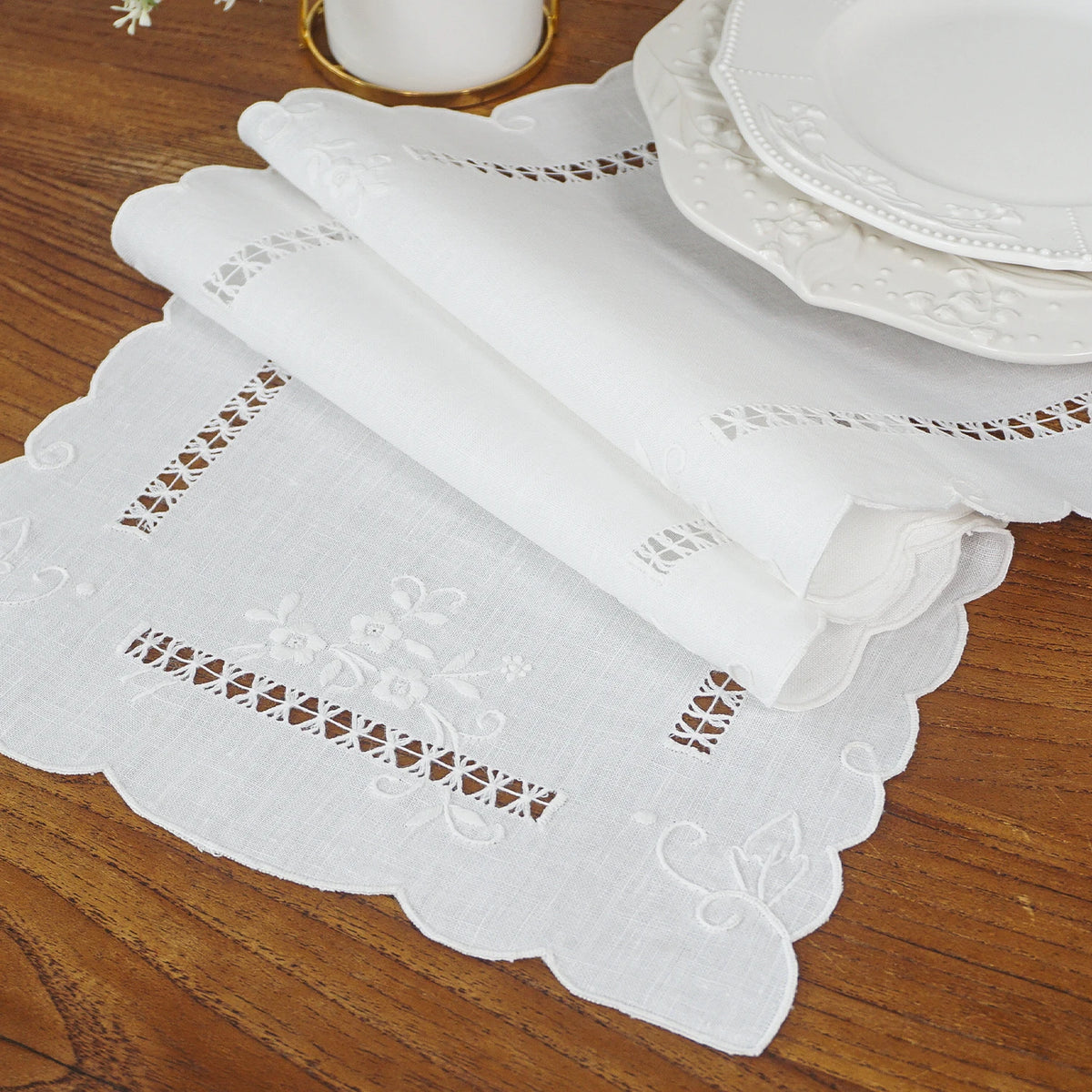 Rolled vintage-style linen table runner showing floral embroidery and decorative edging