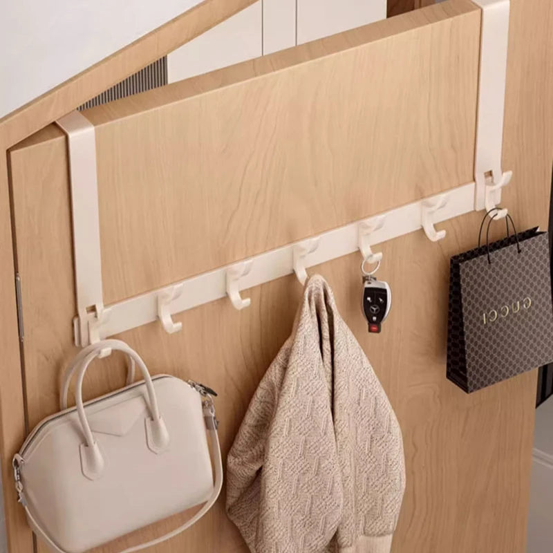 Over-door cream rack with six hooks in use in an entryway, holding a bag and sweater