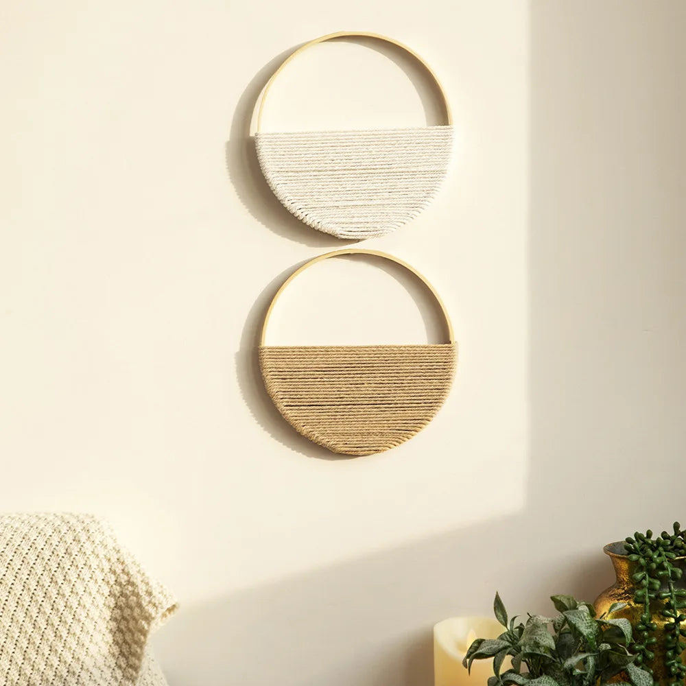 Set of two round macrame wall hangings, one white and one tan, hung on a wall in a sunlit living room