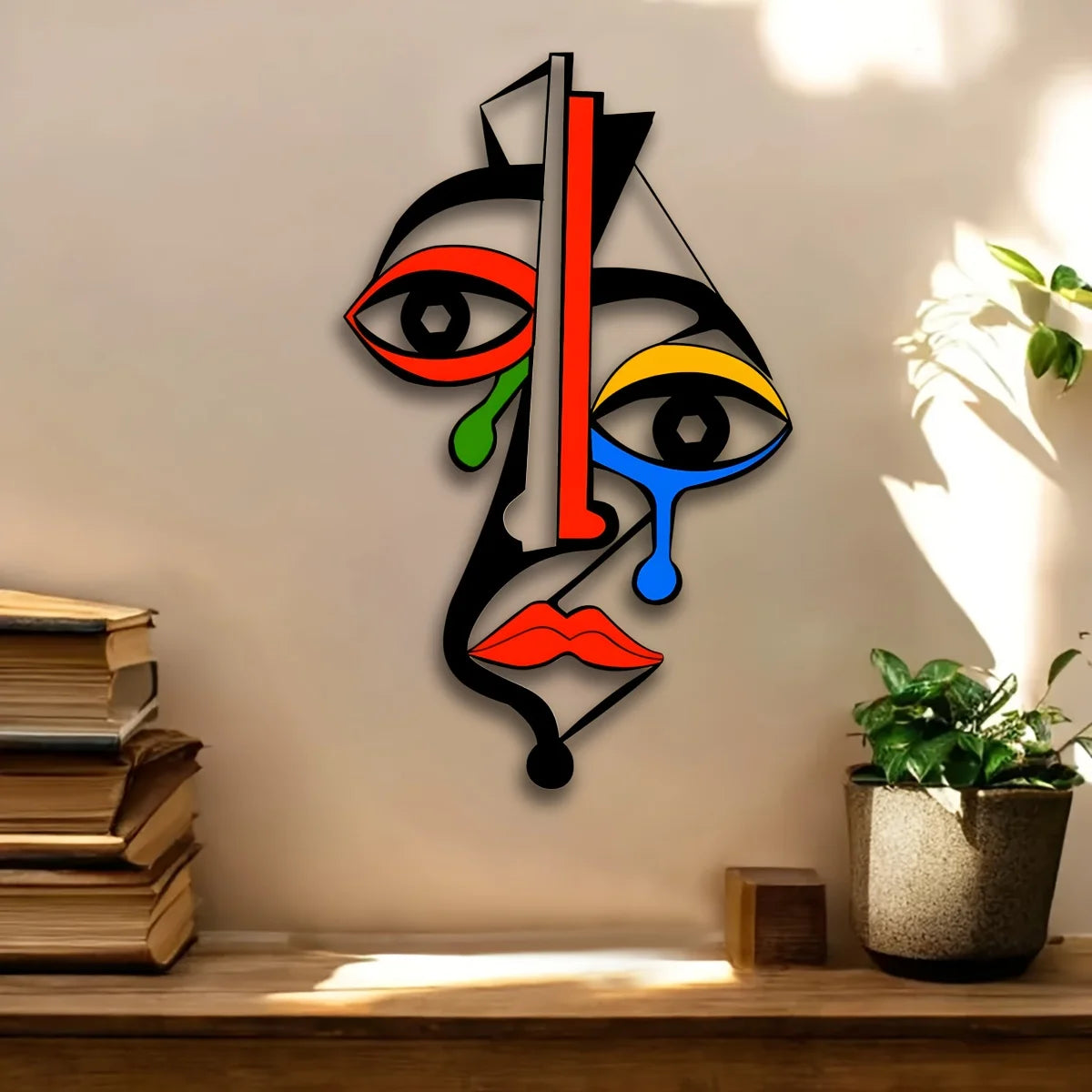 Colorful abstract geometric metal face wall art hanging above books and a potted plant