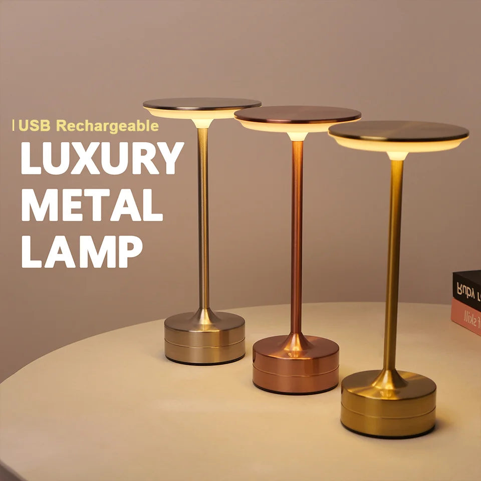 Three metal rechargeable LED touch table lamps in silver, rose gold, and gold, glowing on a table