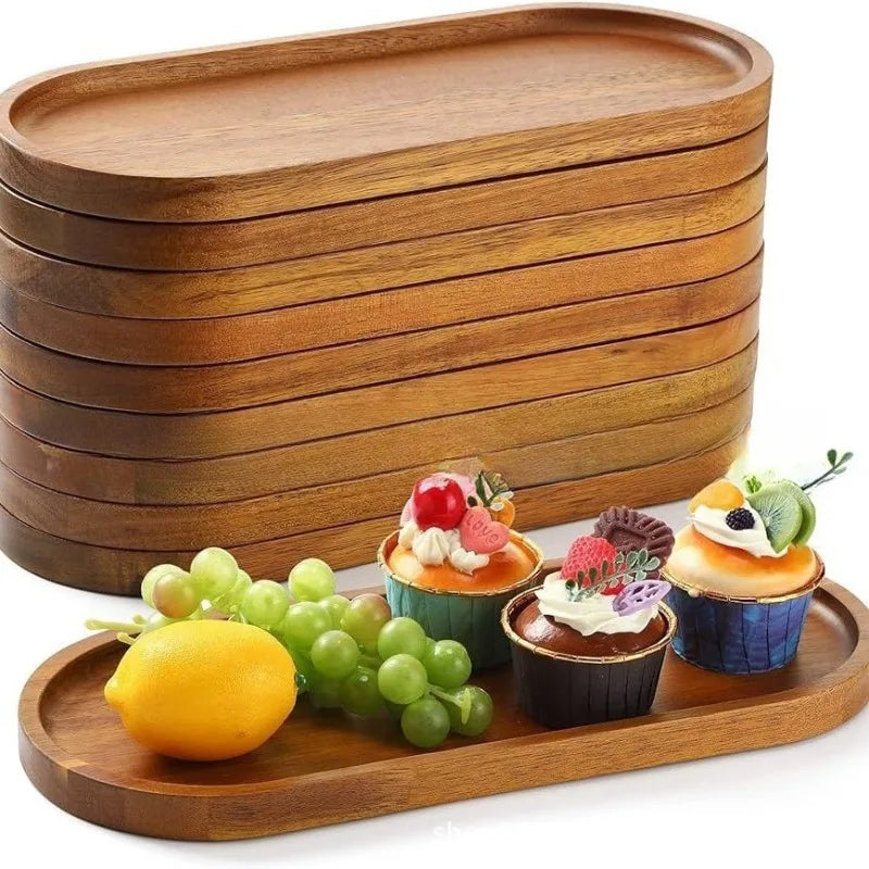 Stack of oval acacia wood trays on a table with fruit and cupcakes arranged for serving