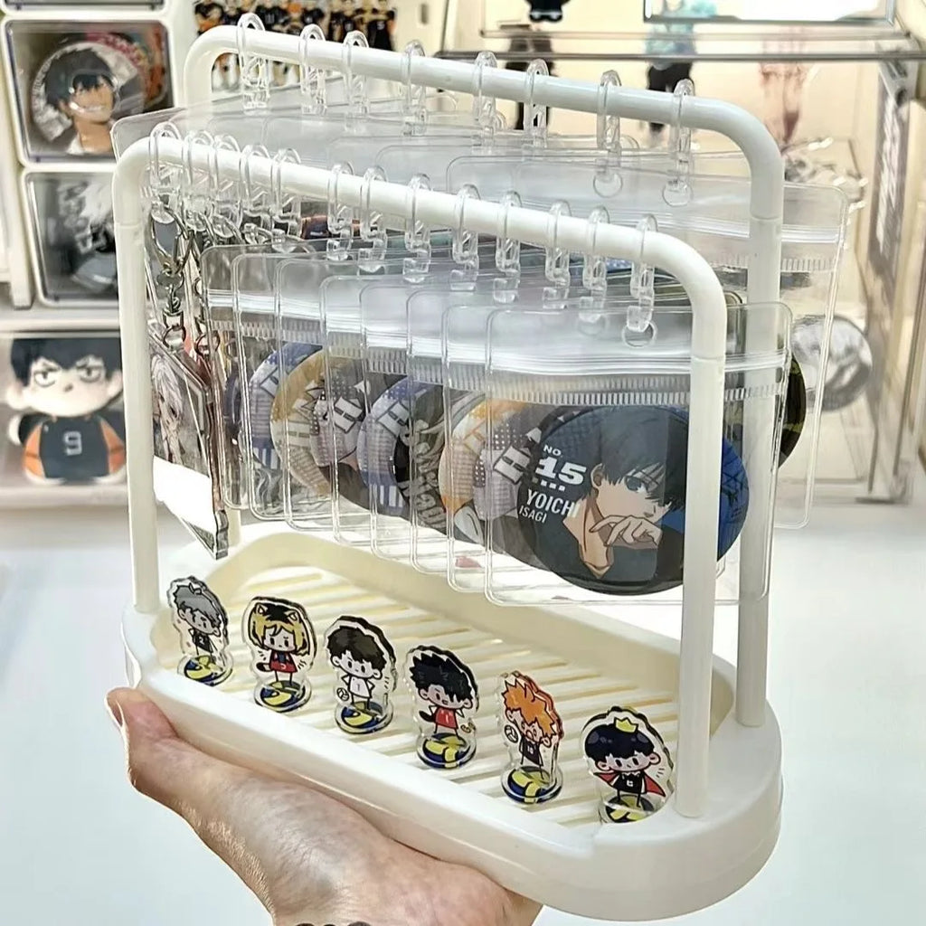 Hand holds a compact white display stand with badges, keychains, and small figures organized