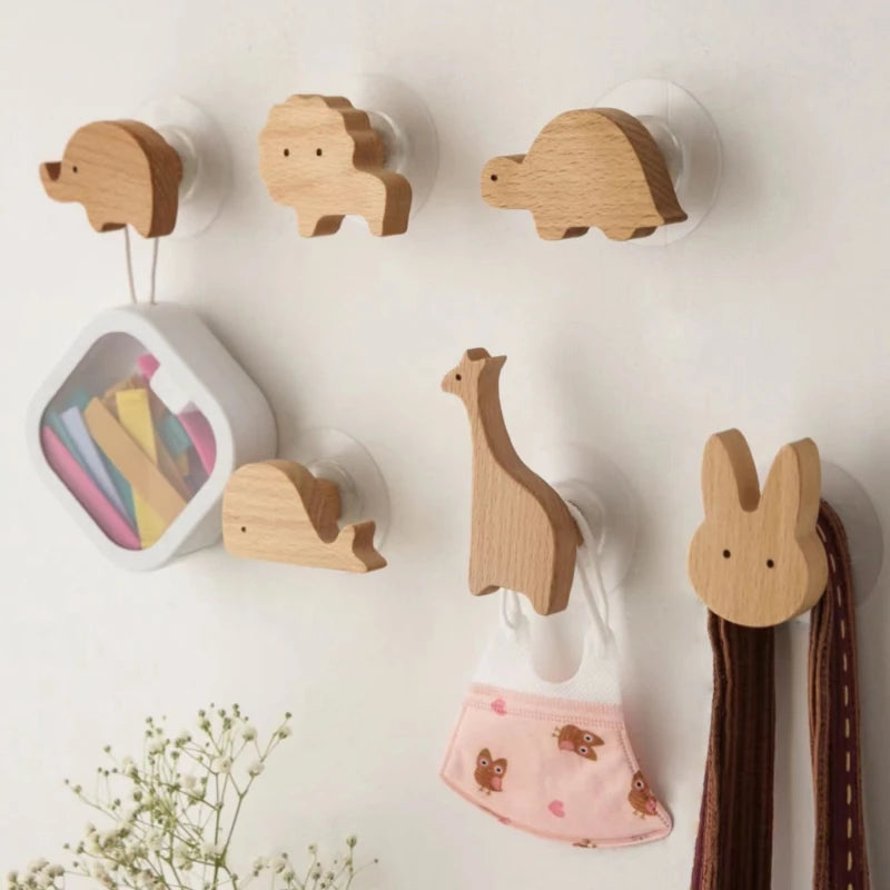 Set of animal-shaped wooden wall hooks mounted in a kids room, holding accessories