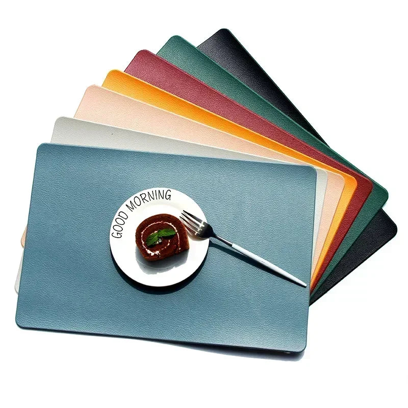 Stack of modern rectangular PVC placemats in seven colors under a plate with a pastry and fork