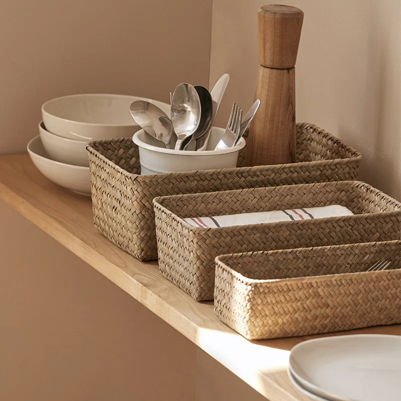 Set of seagrass baskets used to organize utensils and napkins on a kitchen shelf