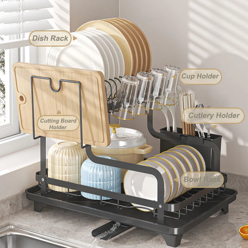 Black 2-tier dish drying rack on countertop with labeled holders for plates, glasses, utensils and cutting board