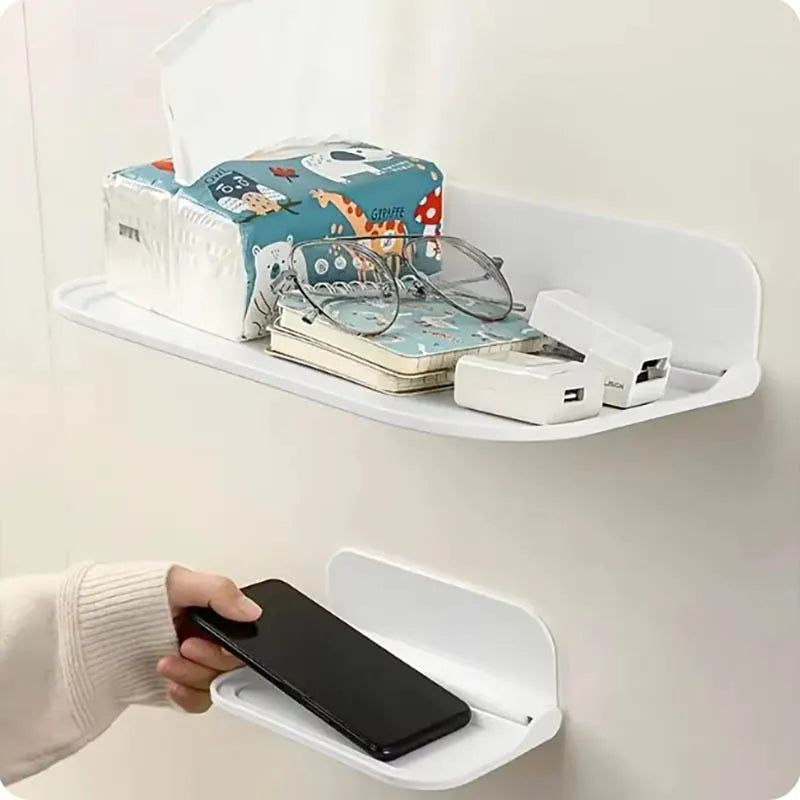 Two white foldable wall shelves, one holding tissues, glasses, notebook, and chargers while the other stores a phone