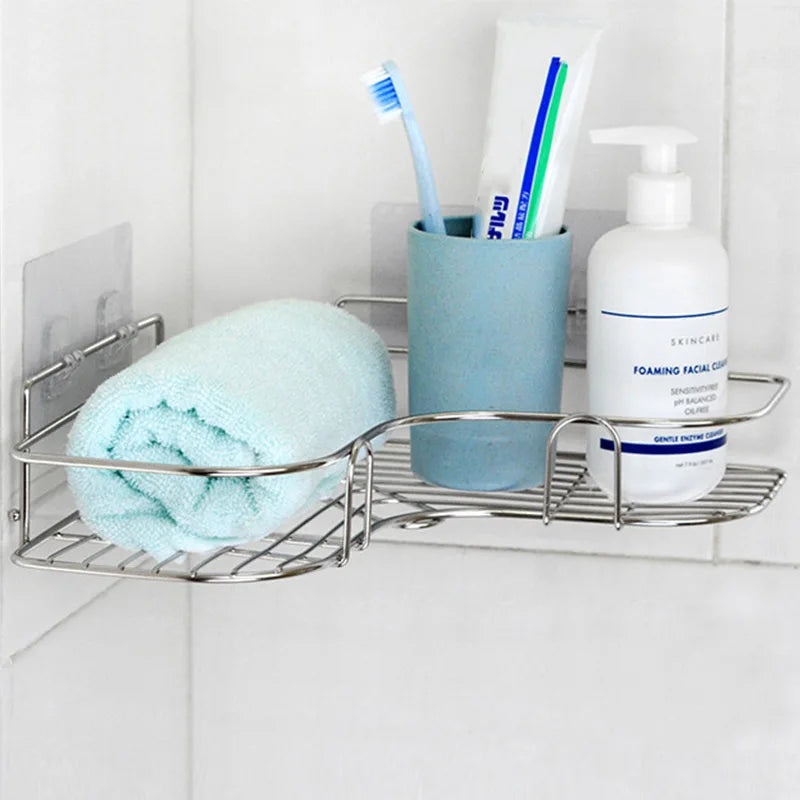 Stainless steel adhesive triangle corner shelf installed in a bathroom, organized with a towel, toothbrush holder, and soap dispenser.