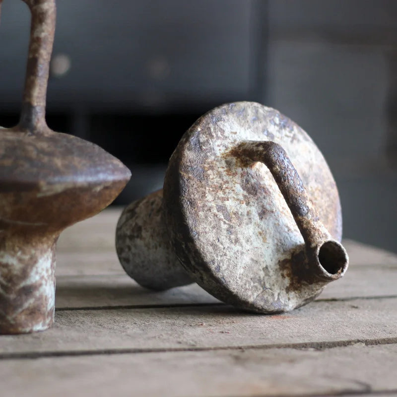 Ceramic vase with low handle laying on its side to show base and handle detail