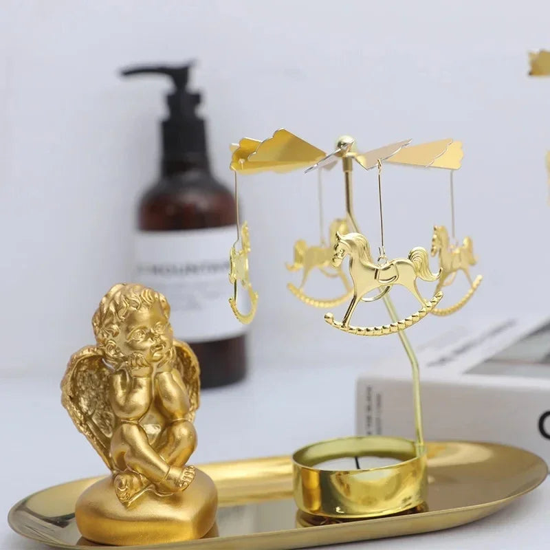 Gold carousel motif rotating tealight candle holder displayed on a tray with a gold angel figurine