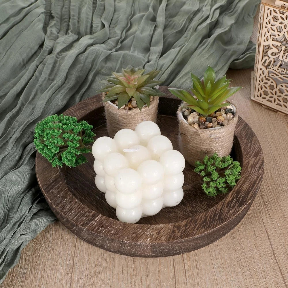 Distressed wood tray used for candles and small faux succulents on a soft green fabric background