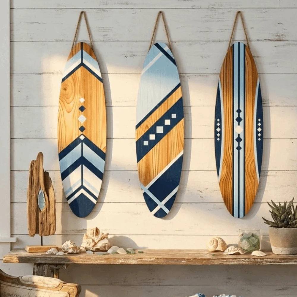 Set of three wooden surfboard wall decor pieces with blue and natural designs hanging on a white shiplap wall in a beach-style entryway.