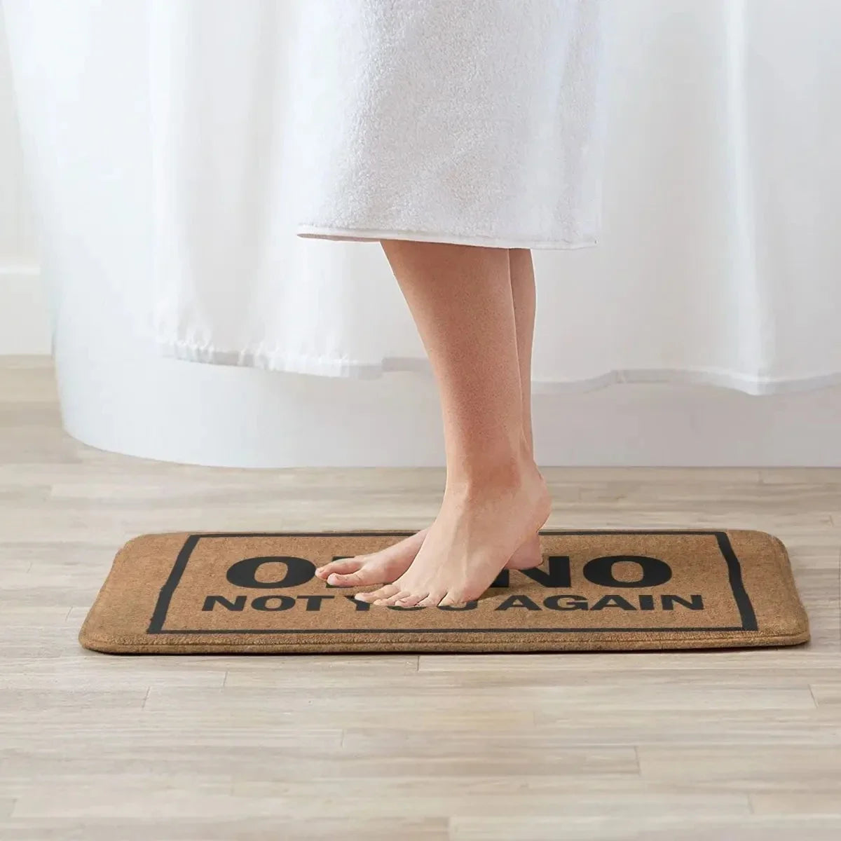 Person standing barefoot on the 'Oh No Not You Again' mat in a bathroom